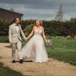 Wedding couple walks on garden path happily.