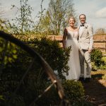 Smiling couple in wedding attire outdoors.