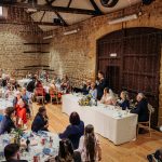 Rustic wedding reception with guests and head table speeches.