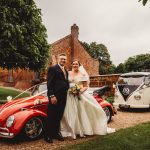 Bride and groom with classic cars.