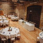 Rustic banquet hall with round tables and decorations.