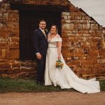 Bride and groom at rustic stone building.