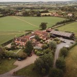 Aerial view of countryside farmhouse and fields.