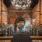 Rustic wedding venue with floral arch and chairs.