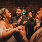 Wedding guests dancing and smiling indoors.