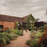 Rustic brick building with lush garden pathway