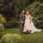 Bride and groom with dogs in garden wedding.