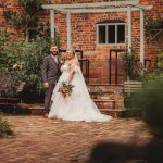 Couple in wedding attire in garden setting.