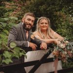 Bride and groom posing by garden fence