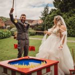 Bride and groom playing hook-a-duck game at wedding.