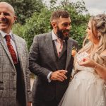 Smiling wedding guests enjoying a card trick.