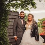 Couple in wedding attire, garden setting.