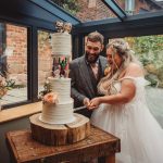 Bride and groom cutting white wedding cake together.