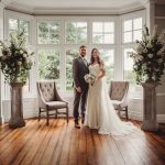 Happy couple posing at elegant indoor wedding ceremony.