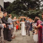 Bride and groom walking through confetti celebration.