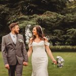 Bride and groom walking in garden, wedding bouquet