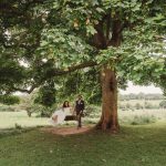 Couple on swing under large tree in countryside.