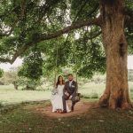 Bride and groom on swing under tree