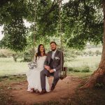 Bride and groom sitting on tree swing.