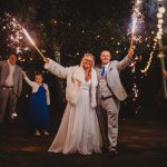 Couple celebrating with sparklers at night wedding