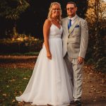 Bride and groom pose on autumn pathway