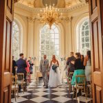 Bride and groom walking in grand ceremony hall.