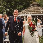 Happy couple walking down the aisle, confetti celebration.