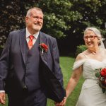 Smiling couple holding hands on wedding day.