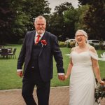 Smiling couple holding hands at garden wedding