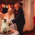 Couple cutting wedding cake at reception.