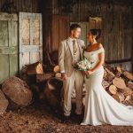 Bride and groom standing in rustic barn setting.