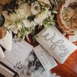 Wedding accessories and invitations on wooden table.