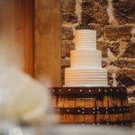 Three-tier wedding cake on rustic barrel table.