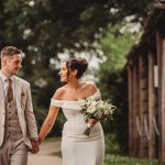 Bride and groom walking, holding hands outside.