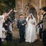 Bride and groom under confetti at church wedding.