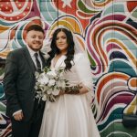 Bride and groom in front of colourful mural.