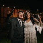 Bride and groom celebrating with champagne outdoors.