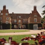 Historic English manor house with gardens and driveway.