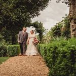 Bride and groom walking through garden path