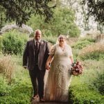 Bride and groom walking in garden.