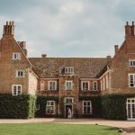 Historic brick mansion with ivy and large chimneys.