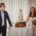 Bride and groom standing by wedding cake table.