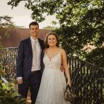 Smiling couple on a garden bridge, wedding attire.