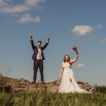 Bride and groom celebrating outdoors on a sunny day.