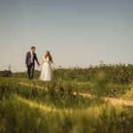 Bride and groom walking in sunny countryside