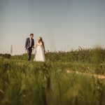 Bride and groom walking in grassy field