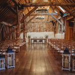 Rustic barn wedding venue with wooden beams and chairs.