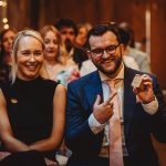 Smiling couple at event, man holding small item.