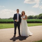 Bride and groom standing on countryside path.