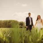 Wedding couple holding hands in a sunny field.